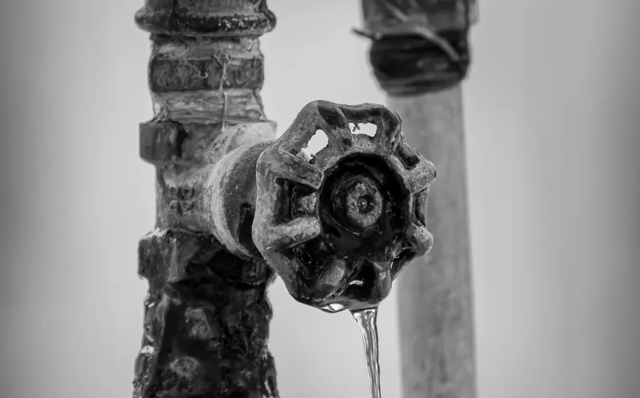 Llave de paso antigua de fierro goteando agua