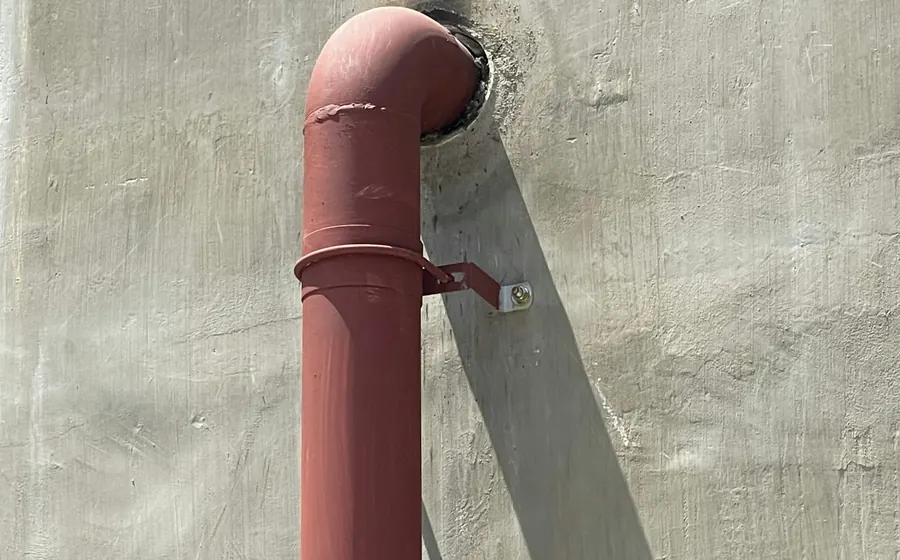 Cañería de gas roja saliendo de un muro de concreto
